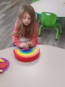 Preschooler stacking a wooden rainbow toy